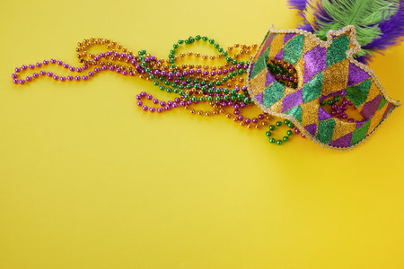 Mardi gras or carnival mask with beads on yellow background. Venetian mask.の写真素材