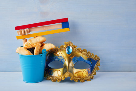 Purim celebration concept with hamantashen cookies, Purim mask and toy noisemaker on blue backgroundの写真素材