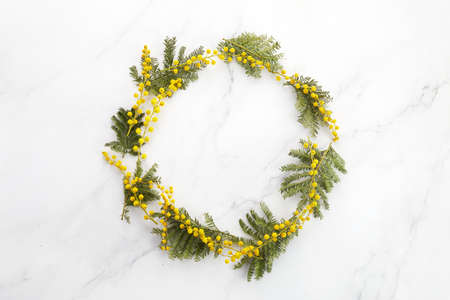 Wreath made of mimosa flowers on marble background. Flat lay, top view, copy space.の写真素材