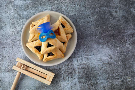 Purim celebration concept with hamantashen cookies, Purim mask and toy noisemaker on grey backgroundの写真素材