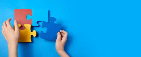Top view hands of a autistic child arranging color puzzle symbol of awareness for autism spectrum disorder. Autism Awareness Day or month.の写真素材