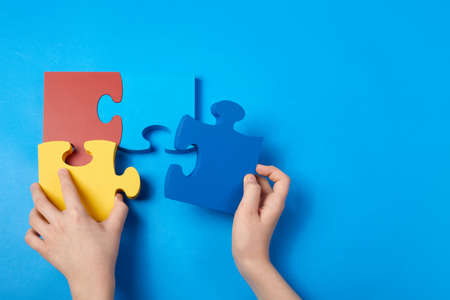 Top view hands of a autistic child arranging color puzzle symbol of awareness for autism spectrum disorder. Autism Awareness Day or month.の写真素材