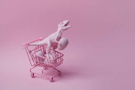 T rex dinosaur with shopping cart and eggs on pink background. Easter mega sale concept.の写真素材
