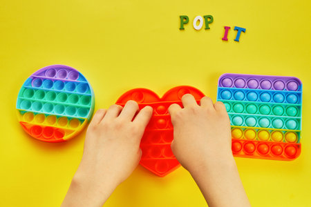 Kid hands playing with colorful pop It fidget toy. Colorful antistress sensory toy fidget push pop it.の写真素材
