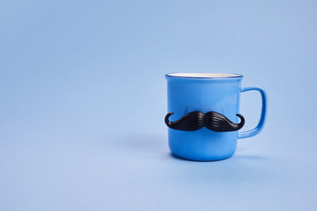 Coffee cup with mustache and bow tie on blue background. Happy Fathers Day concept