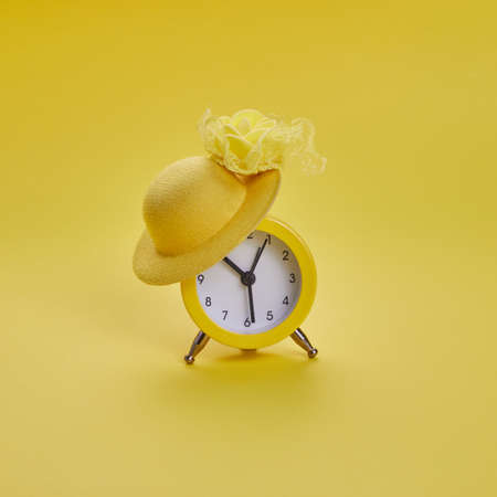 Alarm clock wearing heat on yellow background. Summer time concept.の写真素材