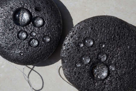 Bamboo charcoal sponge close up with water drops. Face Cleansing and Make Up Removing Beauty Routineの写真素材