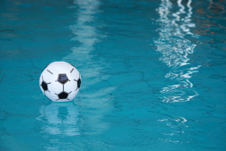 Beach ball in pool. Inflatable ball floating in swimming pool.