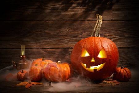 Halloween pumpkin head jack lantern with smoke on dark wooden backgroundの写真素材