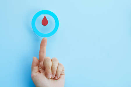 World diabetes day awareness. Woman hand with a blue circle with blood drop, symbol of the diabetesの写真素材