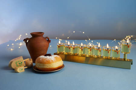 Jewish holiday Hanukkah background with menorah- traditional candelabra, spinning top and doughnut on blue backgroundの写真素材