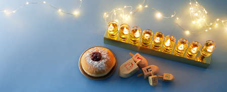 Jewish holiday Hanukkah background with menorah- traditional candelabra, spinning top and doughnut on blue backgroundの写真素材