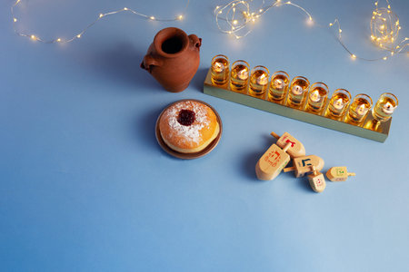 Jewish holiday Hanukkah background with menorah- traditional candelabra, spinning top and doughnut...