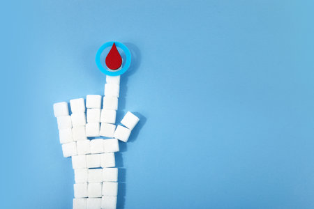 World diabetes day awareness. Blue circle with blood drop and hand shaped sugar cubes.の写真素材