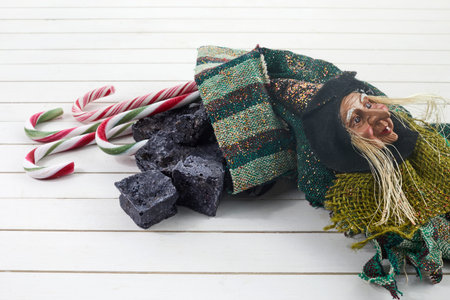 Befana sock with sweet coal and candy on wooden background. Italian Epiphany day tradition.