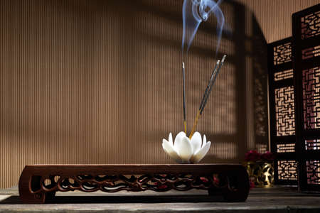 Smoke from burning incense sticks standing on lotus incense holderの写真素材