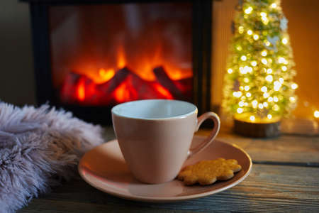 Cup with blanket over fireplace on wooden table. Winter and Christmas holiday conceptの写真素材