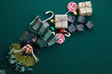 Befana sock with sweet coal and candy on dark greeen background. Italian Epiphany day tradition.の写真素材