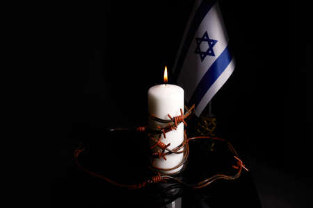 Barbed wire on burning candle and Israel flag on black background with space for text.の写真素材