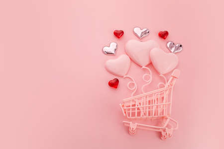 Heart shaped baloons in the pink shopping cart on a pink background. Season sale, spring shoping concept. Valentines day.の写真素材