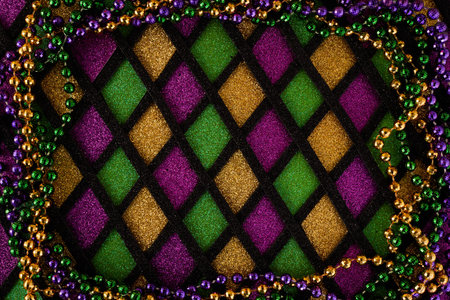 Frame of Mardi Gras Mask and colorful Mardi Gras Beads on diamond shaped background