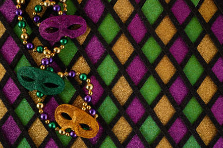 Frame of Mardi Gras Mask and colorful Mardi Gras Beads on diamond shaped backgroundの写真素材