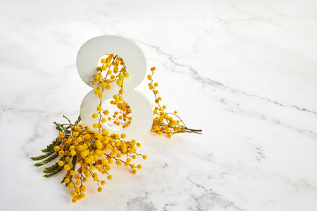 Greeting for International Womens Day on March 8th. Branches of mimosa and number eight.