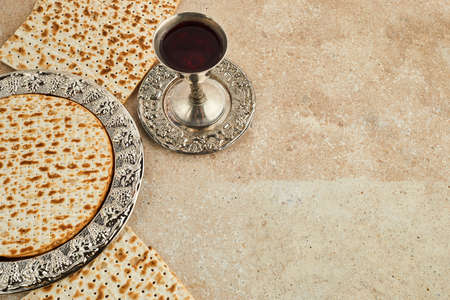 Pesah celebration concept, jewish Passover holiday. Matzah and red kosher. Traditional ritual Jewish bread on travertine stone backgroundの写真素材