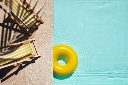 Top view swimming pool with yellow chaise lounge and swimming ring. Summer vacation concept.