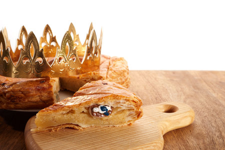 King cake or galette des rois in French. Epiphany pie with golden paper crown and little ceramic figurineの写真素材