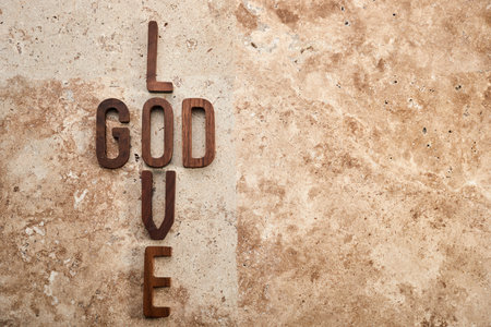God is love concept text lying on the rustic travertine stone background.の写真素材