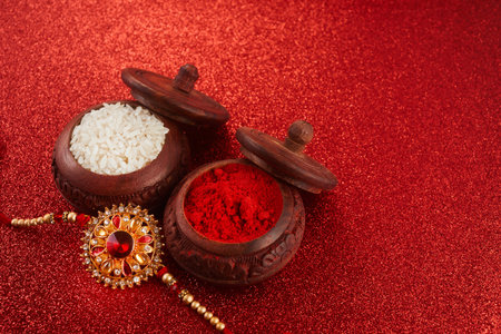 Raksha Bandhan. Rakhi string, Rice Grains and Kumkum on red background.の写真素材