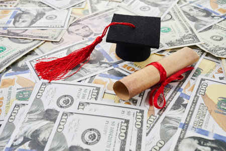 Miniature graduation cap on dollars bills. Student debt crisisの写真素材