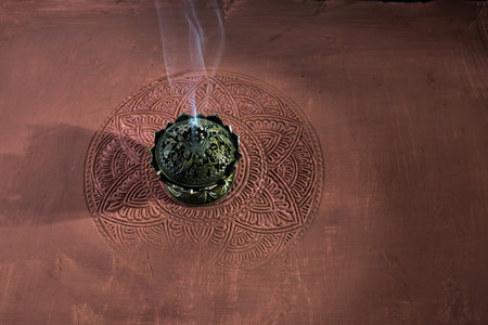 Smoke from burning incense sticks on brown decorative background.