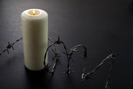 Holocaust memory day. Arbed wire and burning candle on black backgroundの写真素材