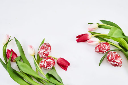Beautiful tulips with colorful eggs on light background. Spring and Easter holiday concept