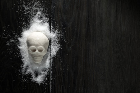 A skull-shaped sugar mound on a wooden surface symbolizing the concept of unhealthy dietの写真素材