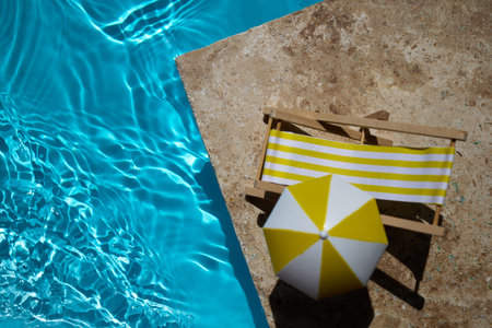 A bright yellow float and mini deck chair beside a pool with clear blue water.