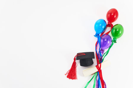 Top view of graduation caps, diplomas, and colorful balloons on white.の写真素材