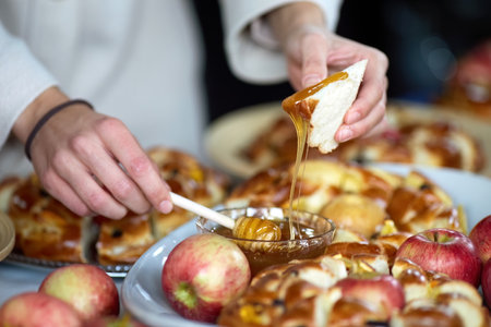 Rosh Hashanah. Jewish New Year celebration. Hands preparing a dessert with apples, honey, and bread.の写真素材