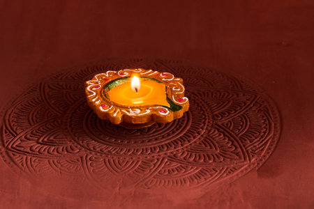 Diwali Diya on Rangoli. A decorative clay diya with a flame