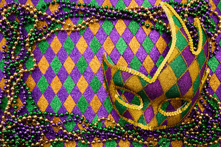 Festive Mardi Gras Display. Colorful Mardi Gras beads on a vibrant harlequin backgroundの写真素材