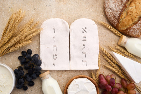 Happy Shavuot concept. Two Stones with Ten Commandments in Ancient Hebrew, Grains, milk and cheeseの写真素材