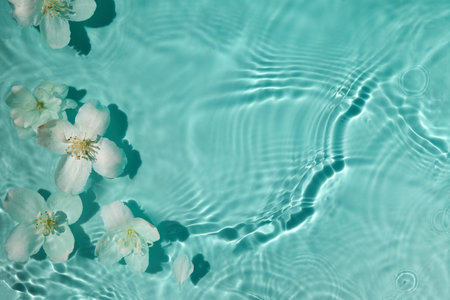 Blossoms on Water. White flowers floating on serene turquoise water with gentle ripples.