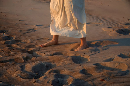 Serenity on the Sand. Silhouette of feet on a sandy beach at sunseの写真素材