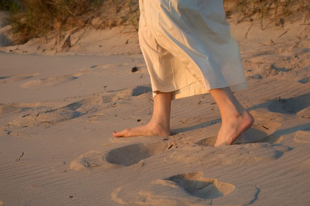 Serene Beach Walk. Silhouette of feet on a sandy beach at sunse