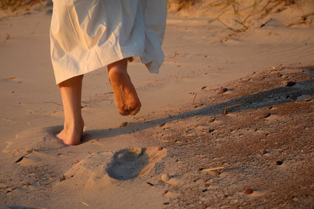 Sunset Stroll. Barefoot walk on sandy beach at sunsetの写真素材