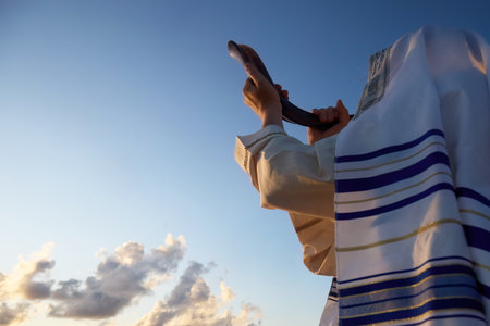 Jewish man blowing the Shofar horn of Rosh Hashanah - New Year. Shofar at Sunsetの写真素材