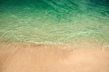 Tranquil Shoreline. Clear turquoise water gently laps against a sandy beach.の写真素材