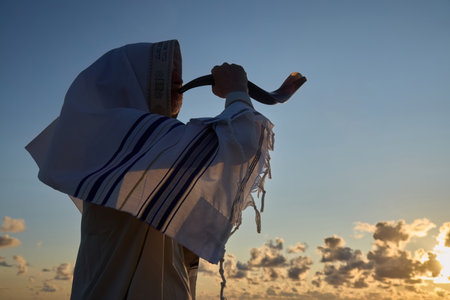 Jewish man blowing the Shofar horn of Rosh Hashanah - New Year. Sunset Shofarの写真素材